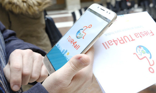 Móvil con app de TUR4all abierta y hoja de Fiesta de TUR4all al lado