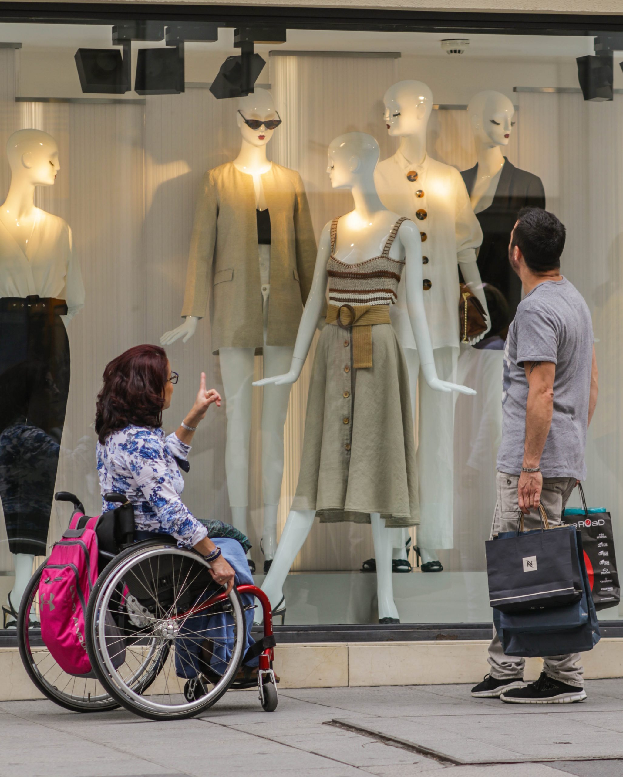 un asistente y una persona en silla de ruedas mirando un escaparate